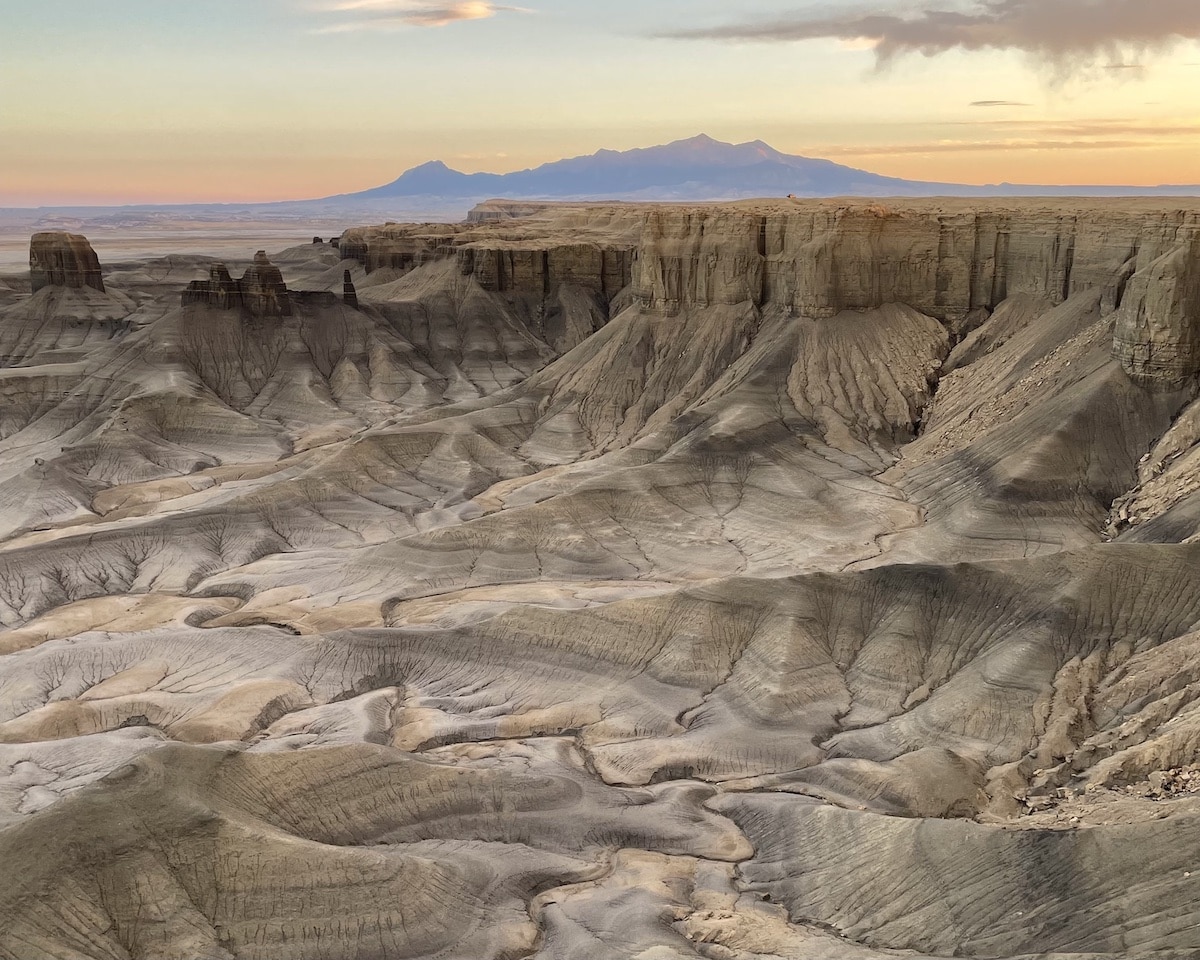 Moonscape Overlook near Hanksville, Utah at sunset with brown rocks and a mountain in the distance